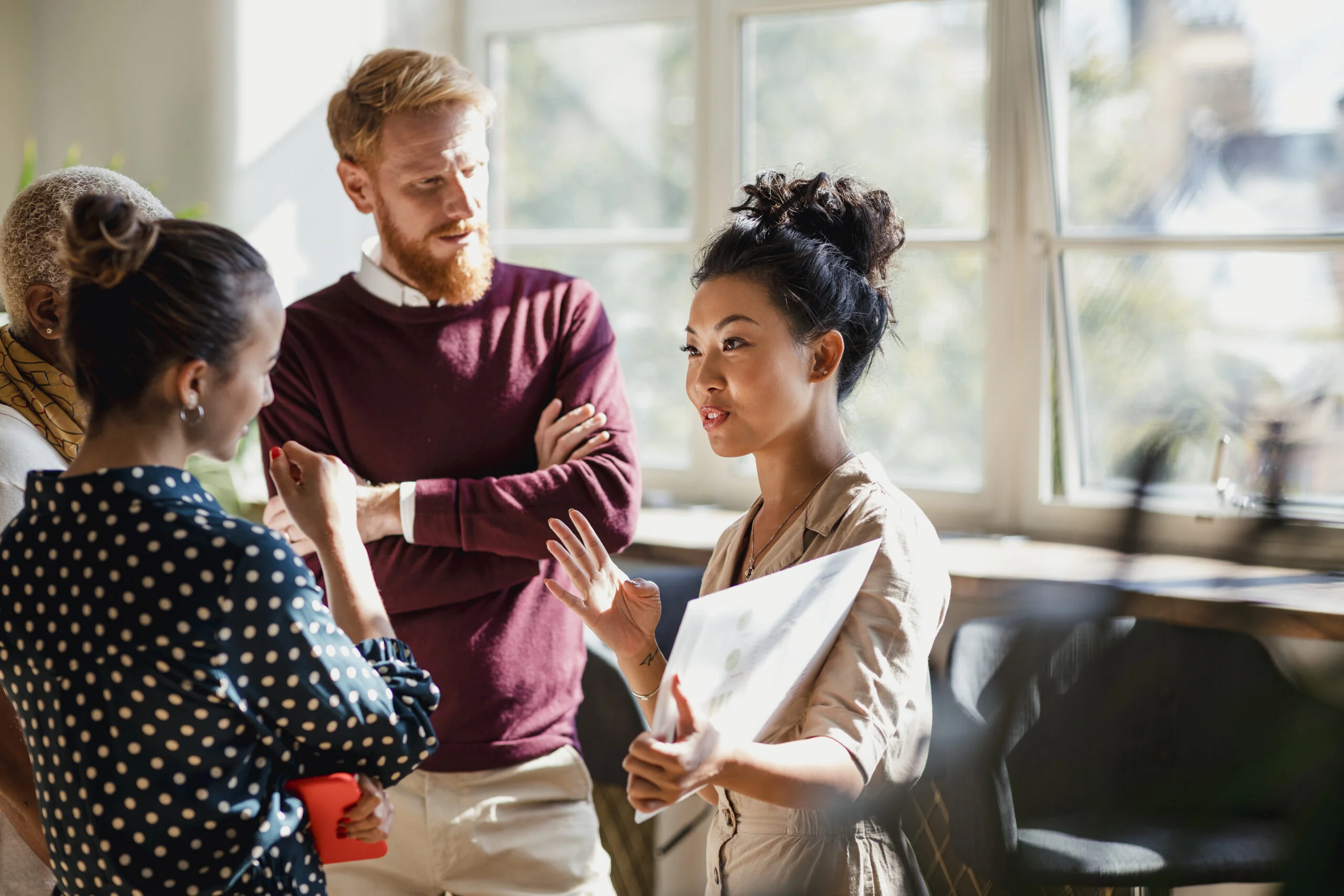A woman investor discussing with members of her team the findings of private equity due diligence for a retail acquisition